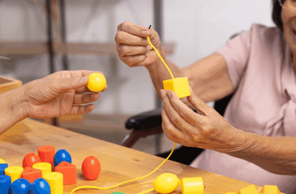 A senior with dementia is playing a stringing beads game to help with motor skills and cognitive function in a memory care community.
