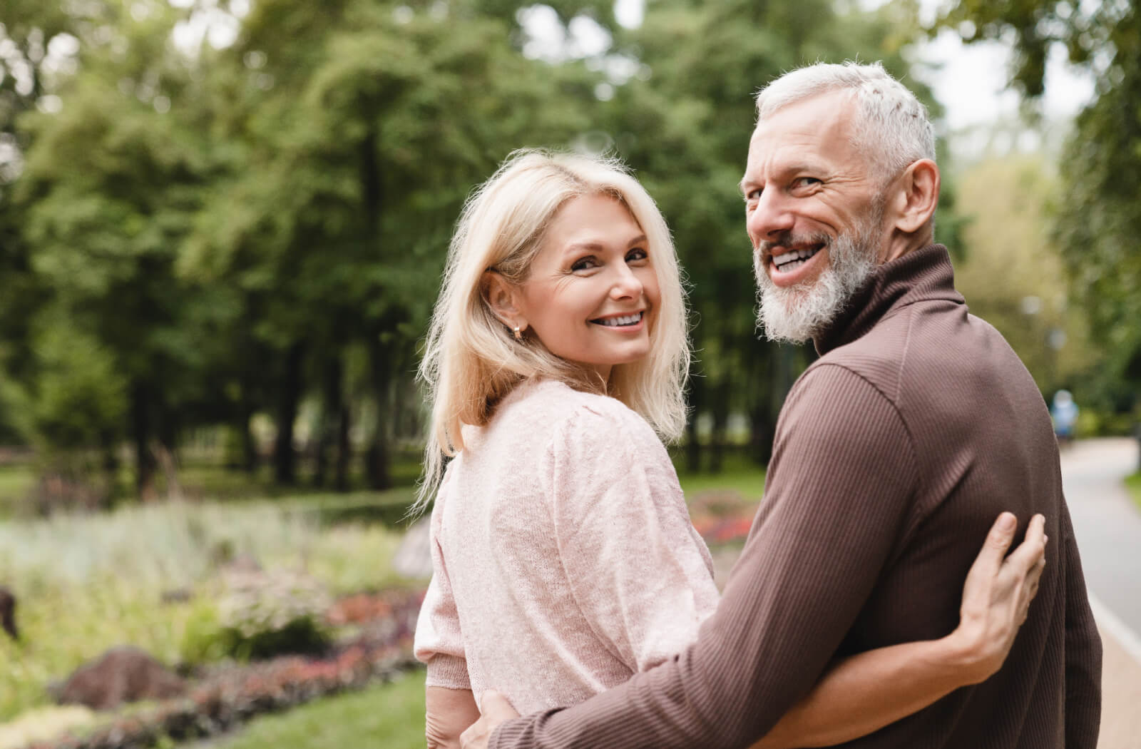 An older adult hugs their spouse while settling into their new kitchen during breakfast time in senior living